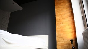 A modern bedroom with a white bed, dark walls, a wooden accent wall, and a radiator. - Spacious 140 m² loft - perfect for families & friends! (Berlin)
