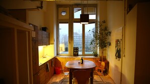 A compact kitchen with a dining table and chairs, a window with a view, and a potted plant. - Spacious 140 m² loft - perfect for families & friends! (Berlin)