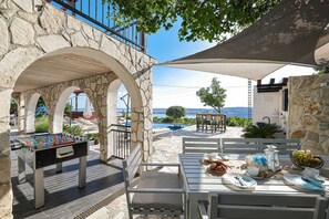 Uma área à beira da piscina com mesa de futebol, assentos externos e vista para o mar.