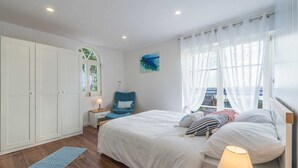 A bedroom with a bed, a chair, a wardrobe, and a window with curtains. - Villa Ventina with Pool (Senj)