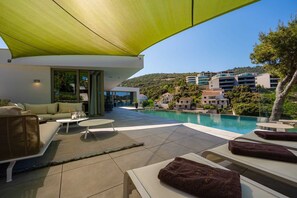 Un espace de détente extérieur moderne, doté d’une piscine, d’un canapé et de fauteuils.