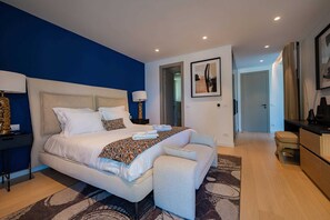 Une chambre moderne avec un grand lit, des tables de chevet, une armoire et une porte donnant sur une autre pièce.