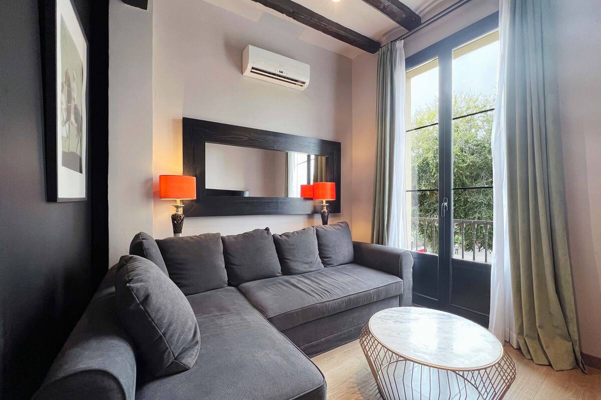 A modern living room with a grey sectional sofa, a round coffee table, and two wall-mounted lamps.