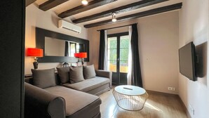 Una sala moderna con un sofá, una mesa redonda de centro y un televisor montado en la pared.