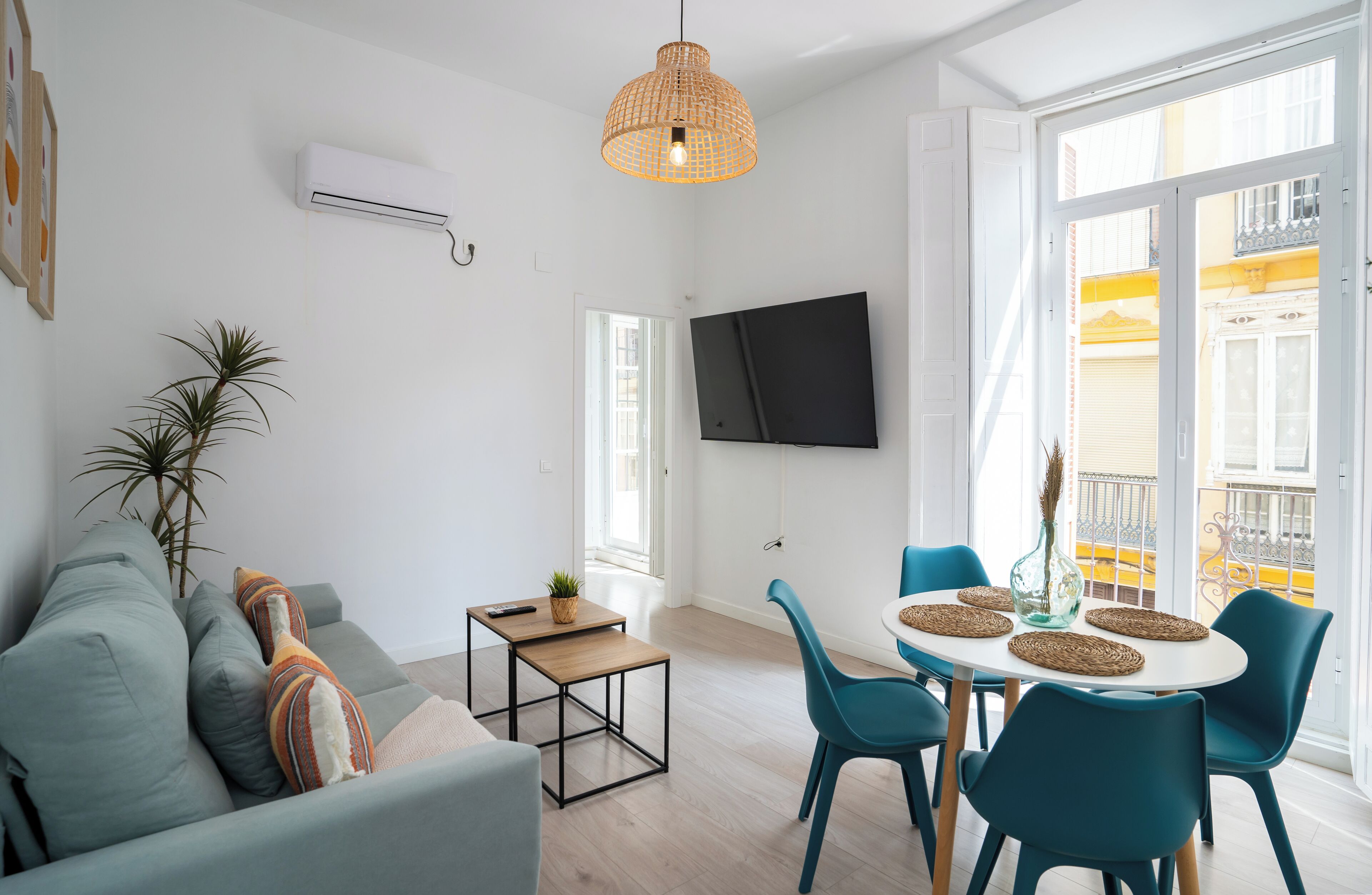 A modern living room with a sofa, a small table, and a dining area with chairs.