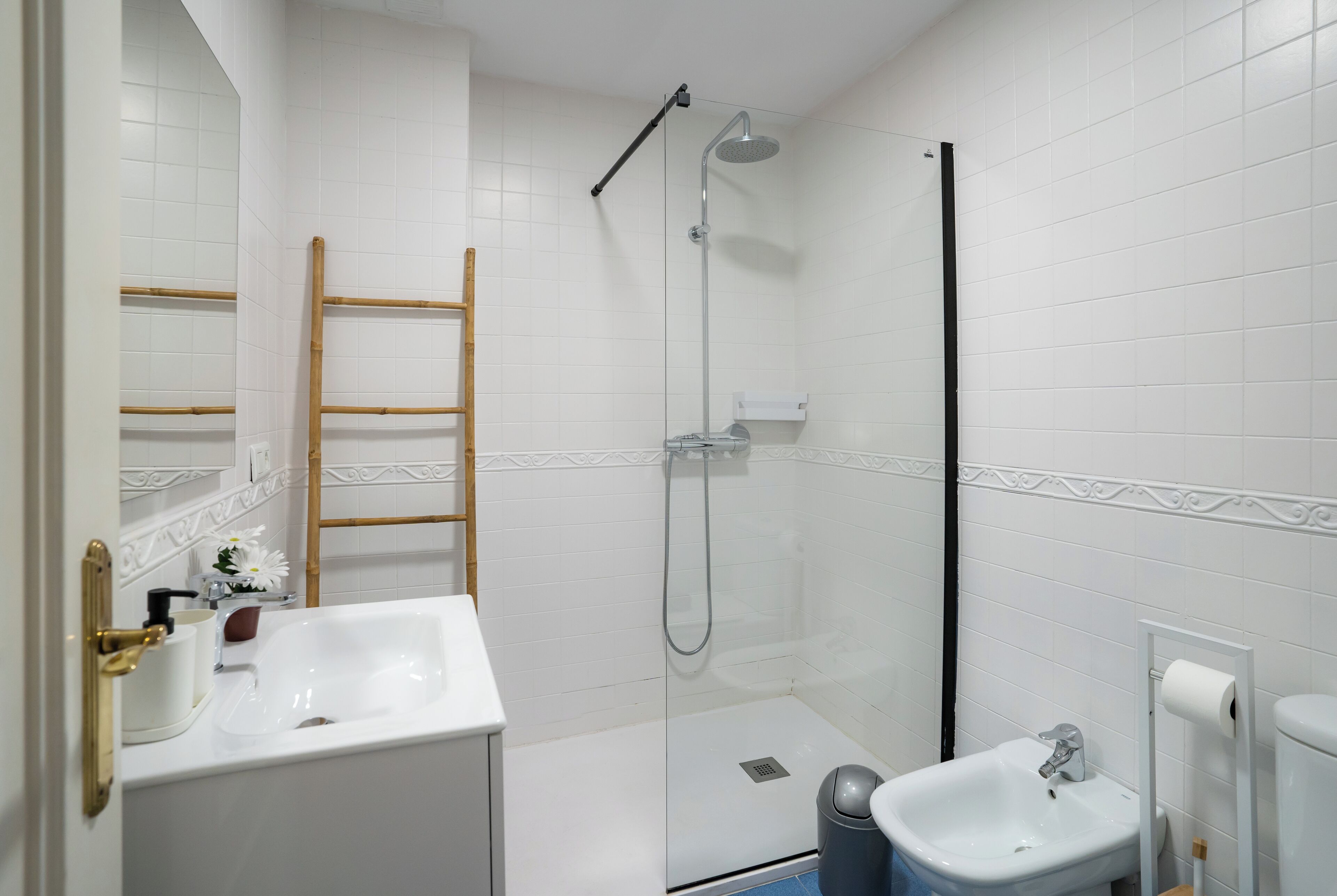 Un baño con cabina de ducha de vidrio, un lavamanos blanco y un inodoro.