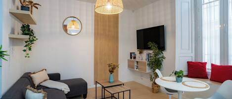 Una sala de estar moderna con un sofá, una mesa de centro, un televisor y un comedor con sillas.