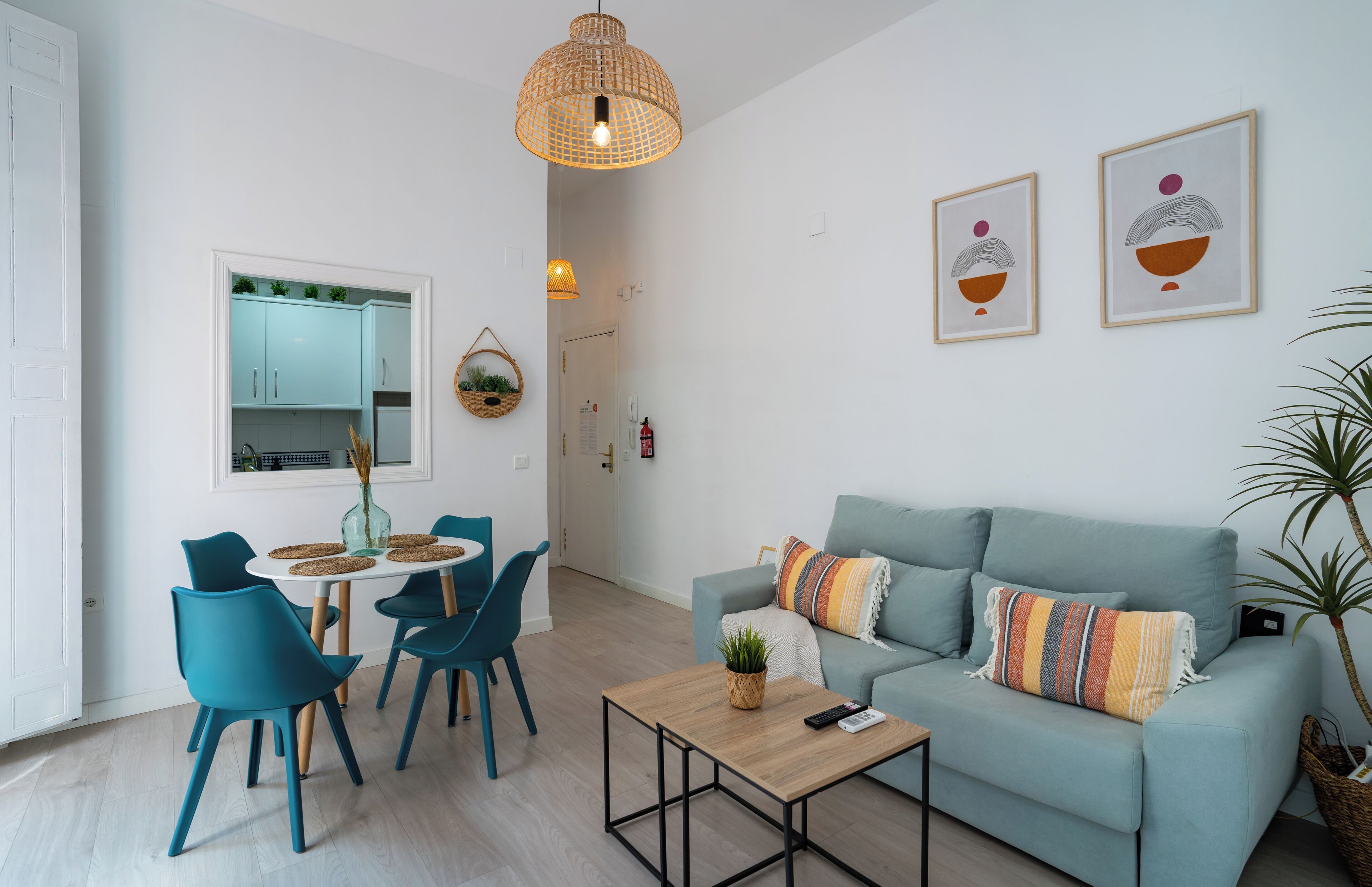 Una sala de estar moderna con sillas color turquesa, un sofá azul claro, una mesa de centro de madera y una lámpara colgante.