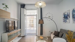 Ein modernes Wohnzimmer mit Fernseher, einer Glasschrank, einem runden Couchtisch und einer Couch.