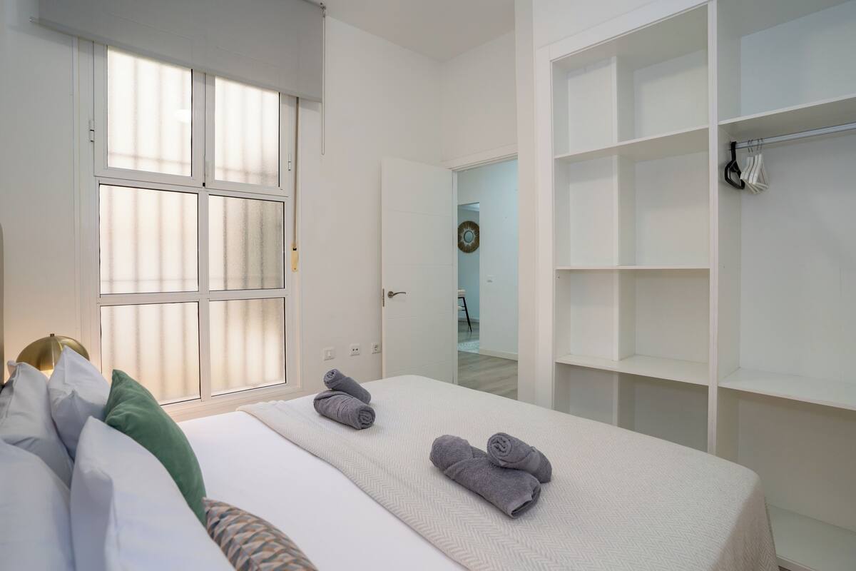 Ein Hotelzimmer mit Bett, Kleiderschrank und Fenster mit Jalousien.