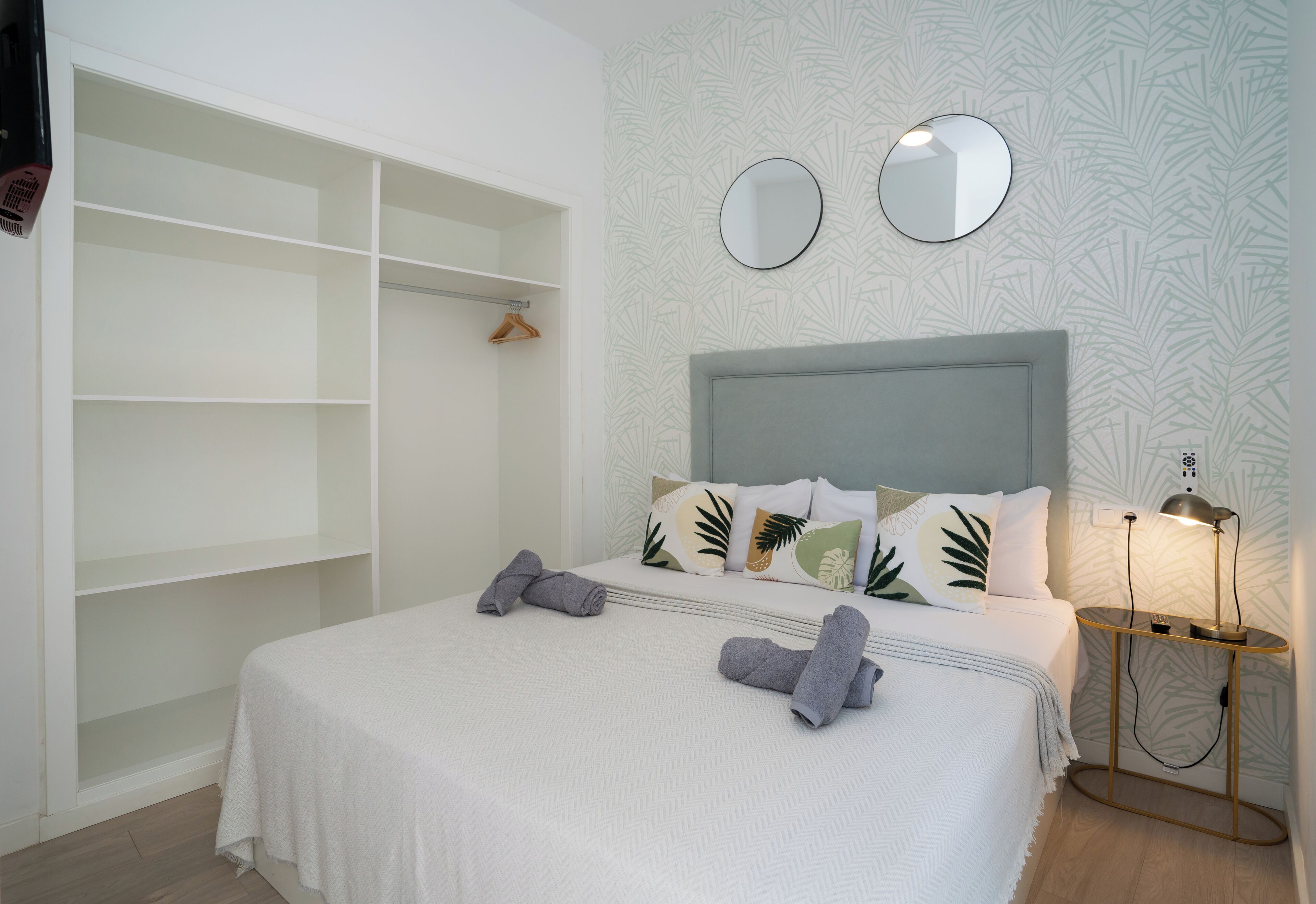 Une chambre à coucher comprenant un lit, une armoire et deux miroirs muraux.