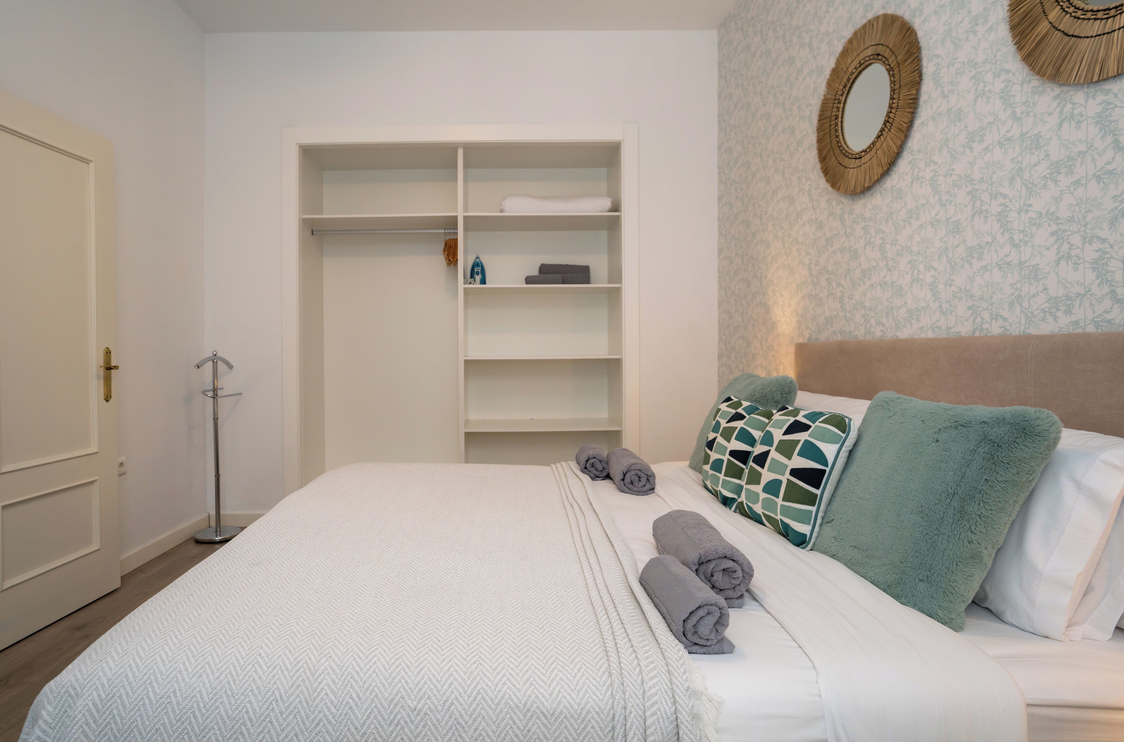 Una habitación de hotel ordenada con cama, armario y espejo en la pared.