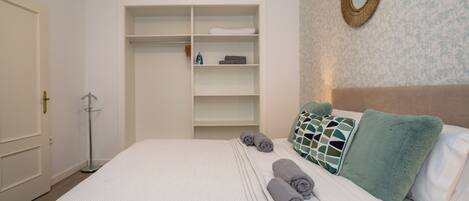 Une chambre d’hôtel bien rangée, avec un lit, une armoire et un miroir au mur.
