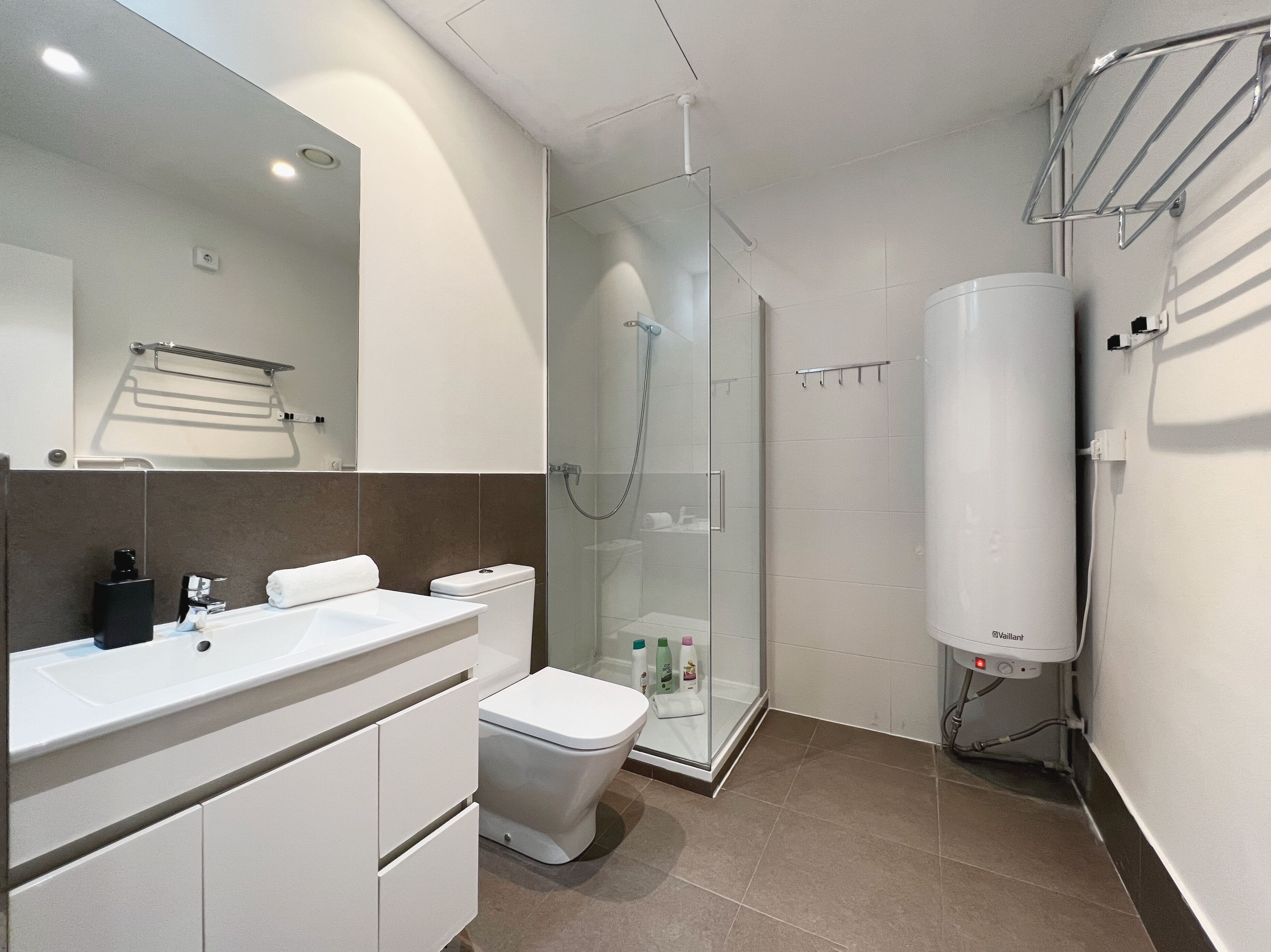 A modern bathroom with a glass-enclosed shower, a white toilet, and a vanity with a mirror.