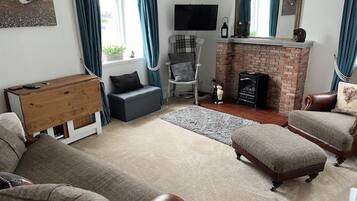 A living room with a fireplace, a television, and a cozy seating area.