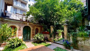 A courtyard with a wooden bench, a brick wall, and a green door. - Detached apartment in seventeenth-century building with indoor garden. (Verona)