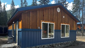 Siniseksi maalattu puinen mökki, jossa on kaksi suurta ikkunaa ja pieni kuisti.