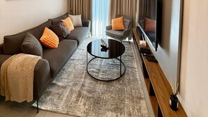 A modern living room with a sofa, armchairs, a coffee table, and a flat-screen TV. - 1-Bedroom Pool View Unit @Nova (Accra)