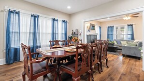 Une salle à manger avec une table et des chaises en bois, une cheminée et un coin salon comprenant un canapé et une table basse.