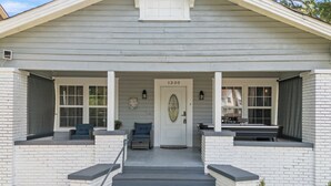 Une maison à deux étages avec un porche à l’avant, le numéro 1330 sur la porte et un petit banc sur le porche.