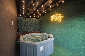 Un jacuzzi dans une pièce avec un mur vert et un néon qui affiche le mot « youme ».