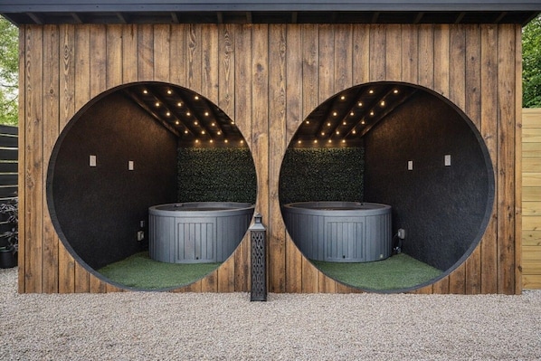 A spa area with two circular hot tubs, each with a wooden wall and a small window.