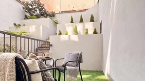A small outdoor seating area with artificial grass, two chairs, and a table with a book and a cup. - TurnKey | National Museum Studio with Patio I (Praha 1)