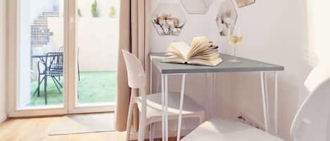Un comedor moderno con una mesa de vidrio, sillas blancas y vistas a un jardín a través de ventanas amplias.