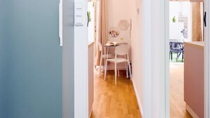 A hallway leading to a dining area with a table and chairs, a window with curtains, and a door on the left. - TurnKey | National Museum Studio with Patio I (Praha 1)
