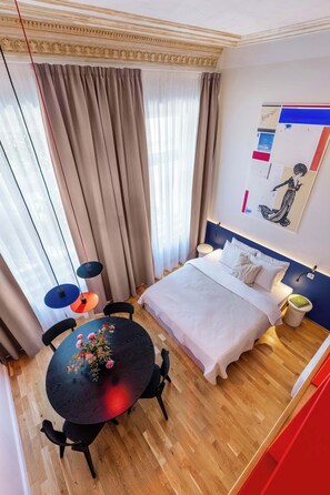 Une chambre d’hôtel comprenant un lit, une table de chevet, une lampe et une table ronde avec des chaises.