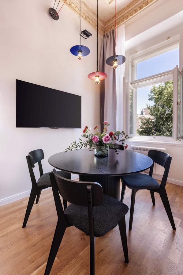 Un coin repas comprenant une table ronde, quatre chaises, un téléviseur à écran plat et un vase de fleurs.