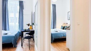 A modern hotel room with two beds, a desk, and a chair.