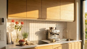A modern kitchen with wooden cabinets, a coffee machine, a sink, and a window with natural light. - TurnKey | Henry's Tower Studio with Terrace III-3 (Hlavní město Praha)