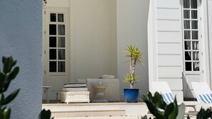 Un edificio blanco con un área de estar techada al aire libre, una planta en maceta y una piscina.