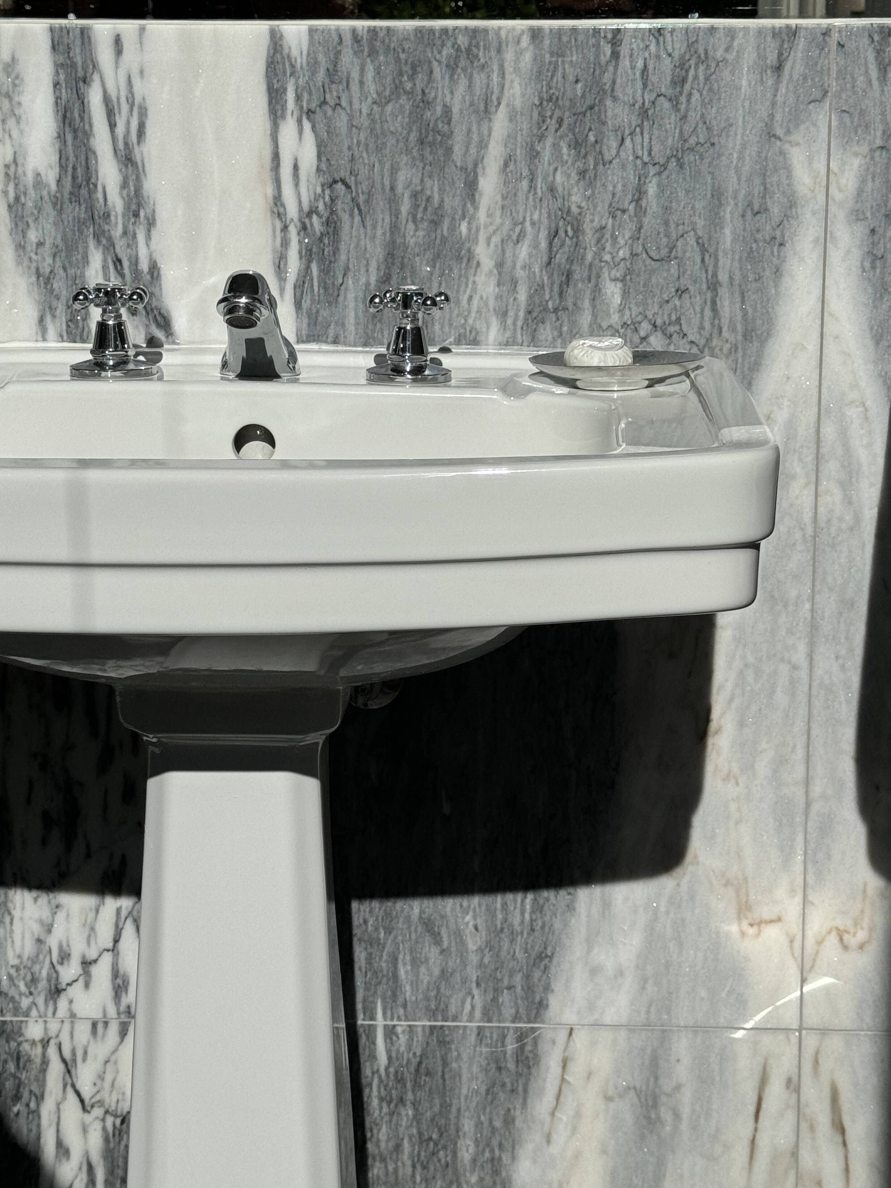 A bathroom sink with a marble backsplash.