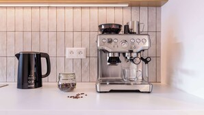 A kitchen with a coffee maker, a kettle, and a jar of coffee beans. - TurnKey | Henry's Tower Apartment IV-2 (Hlavní město Praha)