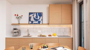 A modern kitchen with wooden cabinets, a coffee machine, and a fruit bowl on the counter.