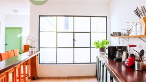 A bright kitchen with a large window, wooden furniture, and various kitchen appliances. - 3 BDR Apt/Private Terrace/ Pet F/Parking/100MB (Oaxaca de Juárez)