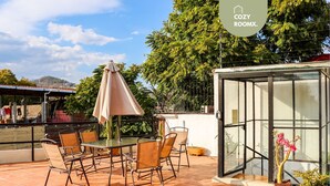 A patio with a table and chairs, a glass greenhouse, and a view of trees and hills. - 3 BDR Apt/Private Terrace/ Pet F/Parking/100MB (Oaxaca de Juárez)
