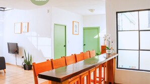 A cozy room with a long wooden table, two green doors, and a large window. - 3 BDR Apt/Private Terrace/ Pet F/Parking/100MB (Oaxaca de Juárez)