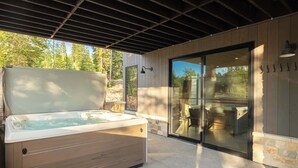 A hot tub under a pergola with a view of a patio area.