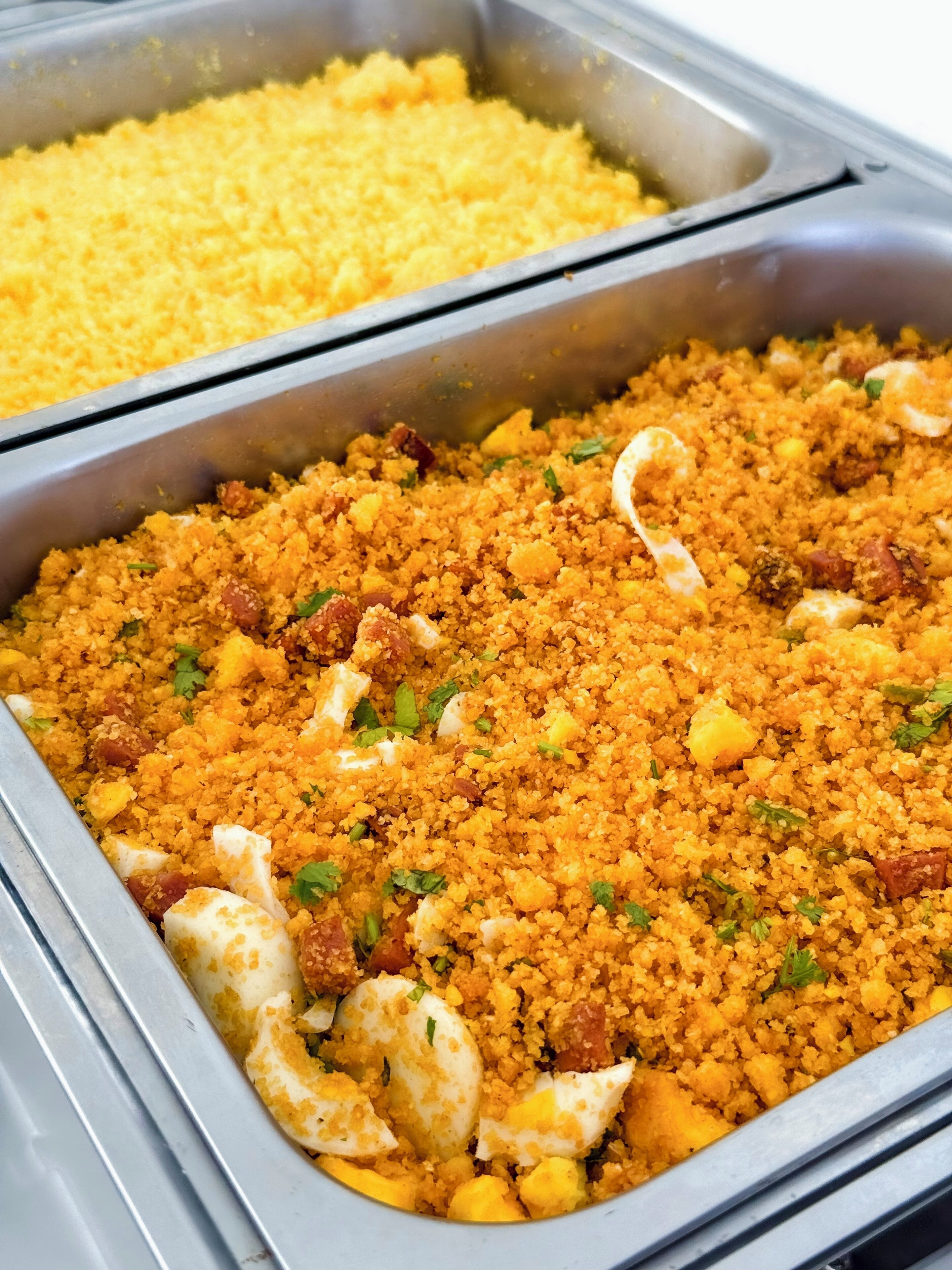 A buffet with various dishes, including a couscous salad with eggs and vegetables.