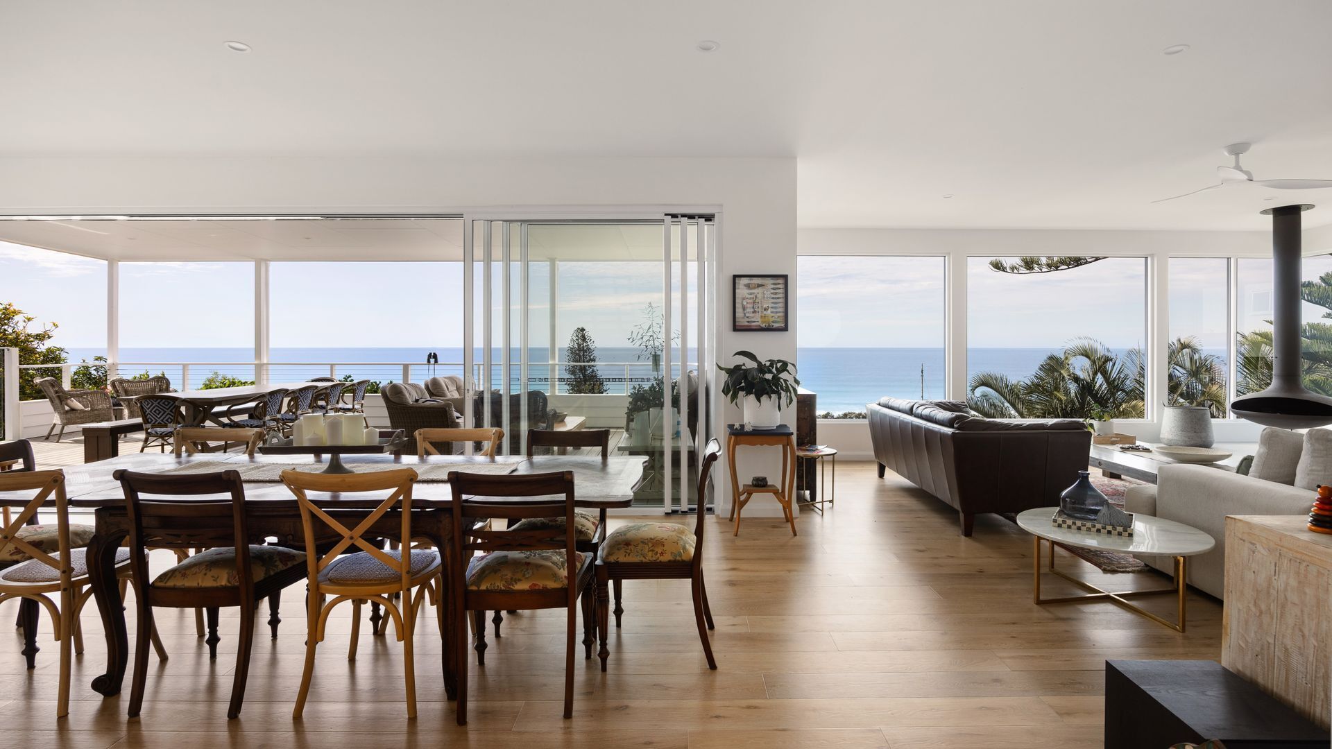 A spacious living area with a large dining table, comfortable seating, and a view of the ocean.