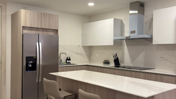 A modern kitchen with a large island, stainless steel refrigerator, and wooden cabinetry. - Vermare 302 in Punta Cana (Punta Cana)