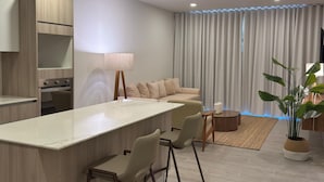 A modern kitchen with a central island, a dining area with chairs, a sofa, and a large window with curtains. - Vermare 302 in Punta Cana (Punta Cana)