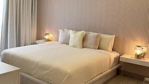 A modern bedroom with a large bed, two bedside tables with lamps, and a wooden floor. - Vermare 302 in Punta Cana (Punta Cana)