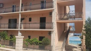 Um edifício residencial de vários andares com varandas, um pilar de pedra e vista para o mar.
