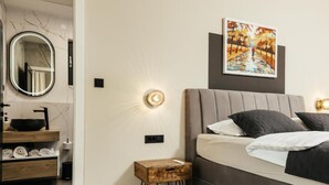 A modern bedroom with a bed, bedside table, and a wall-mounted light fixture.