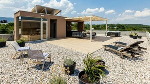 A rooftop terrace with a modern outdoor seating area, a pergola, and potted plants.