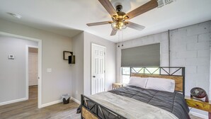Un dormitorio con cama, ventilador de techo, ventana con persianas y suelo de madera.